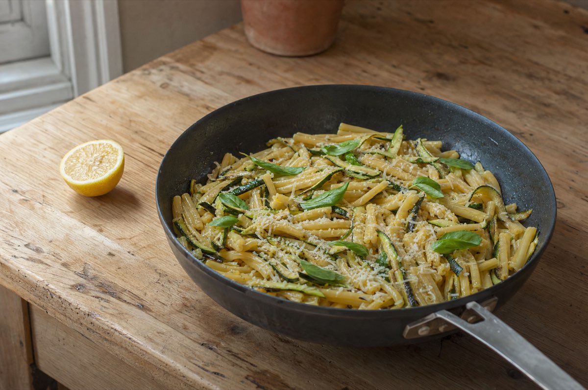 Nudeln mit Zucchinistreifen, Zitronenabrieb und geriebenem Hartkäse in einer Pfanne